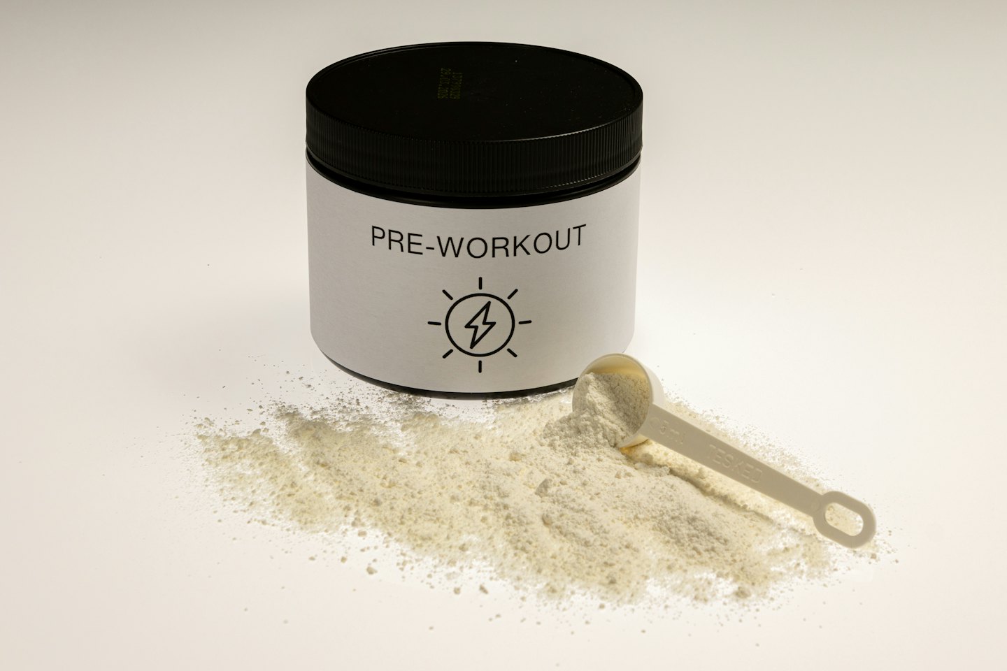 White pre-workout supplement jar with scoop and powder spill.