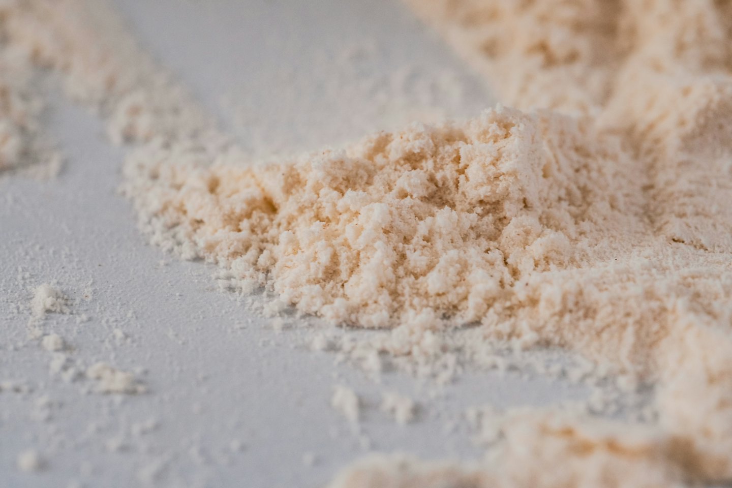 Piles of beige powder scattered on a smooth grey surface.